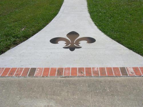 Decorative concrete walkway with brick and a Fleur De Lis