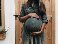 young woman in a dress holding her pregnant belly