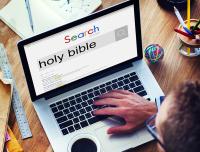 young man typing a search for Holy Bible on his computer