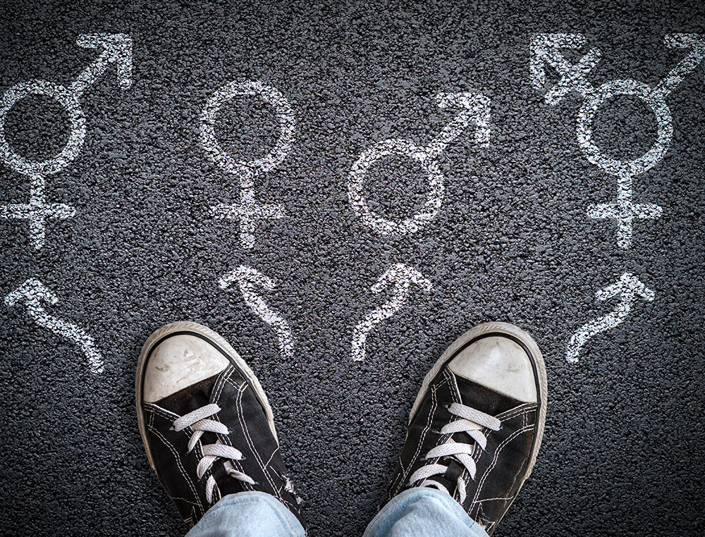 young person's tennis shoes and chalk outlines of gender symbols on the asphalt