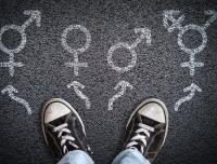 young person's tennis shoes and chalk outlines of gender symbols on the asphalt