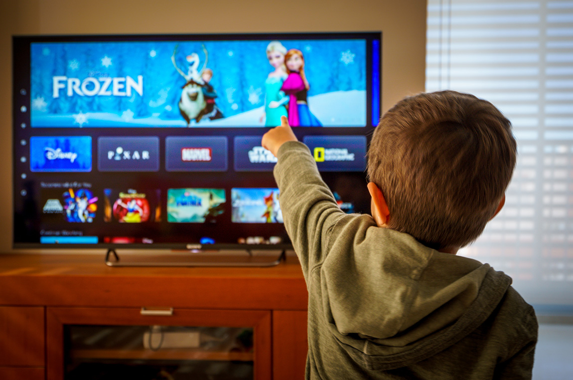 Child pointing to the Disney Plus channel on TV
