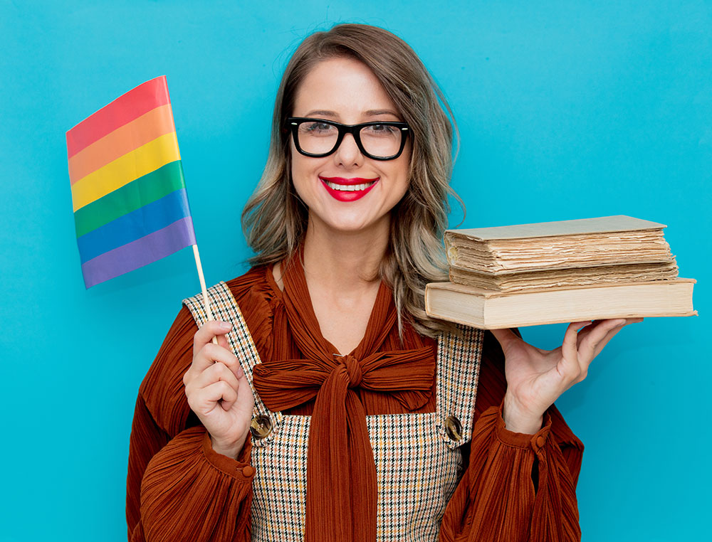 young woman holding LGBT flag and stack of books
