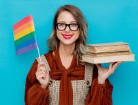 young woman holding LGBT flag and stack of books