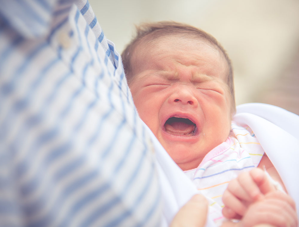 crying baby in mother's arms
