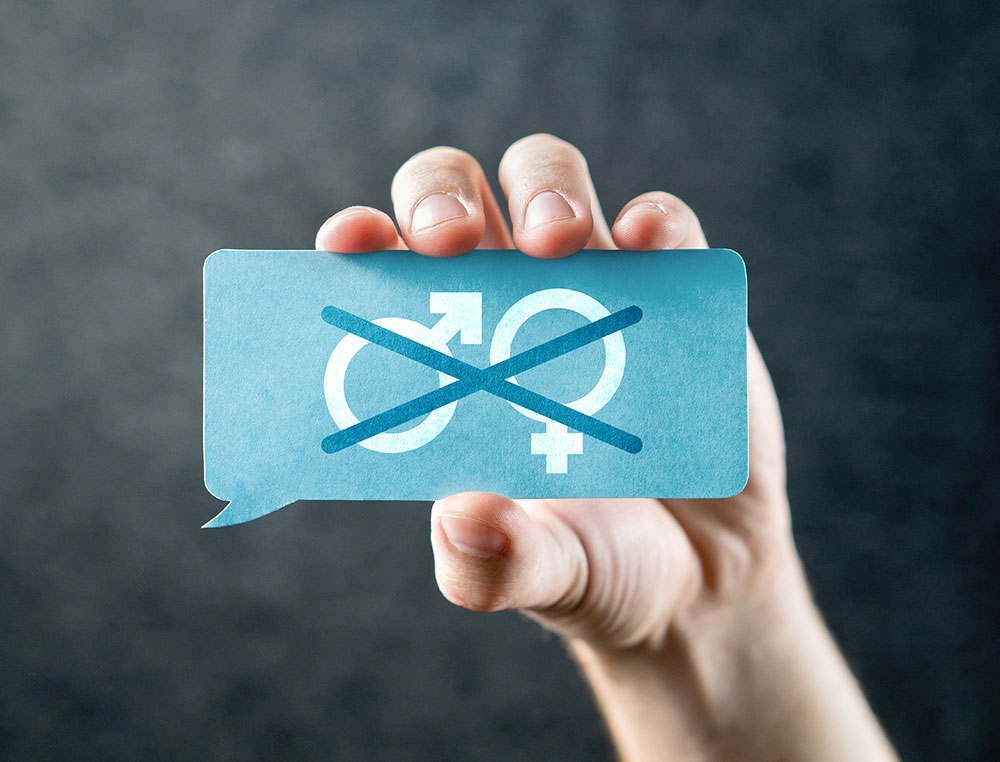 hand holding a card with male and female symbols crossed out