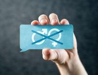 hand holding a card with male and female symbols crossed out