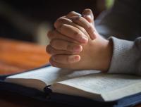 clasped hands on a Bible
