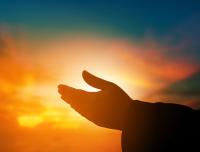 hands raised in prayer at sunset