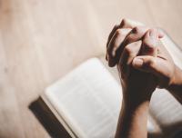 praying hands on an open Bible