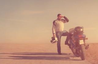 Motorcyclist with one foot on his bike looking out