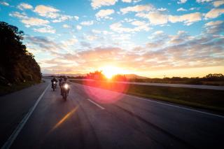 Motorcycle riders on open road with sunset