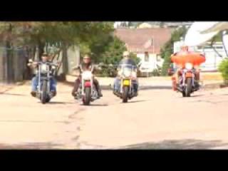 Four motorcyclists riding down a road 