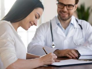 A new patient at Elite Hearing signs important documents for her hearing healthcare. 