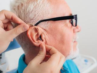 A hearing aid specialist helps a patient adjust their hearing aid settings at Elite Hearing. 