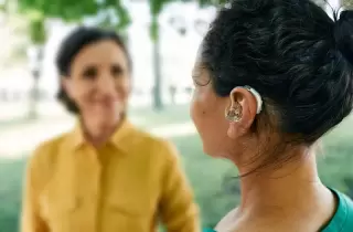 Lady with hearing aid talking to another lady