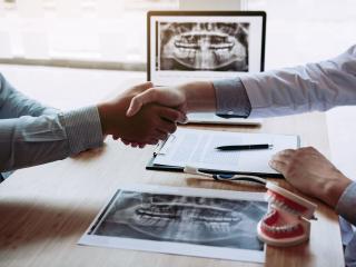shaking hands over dental xrays | Top oral surgeon and orthodontist in Baton Rouge 70809