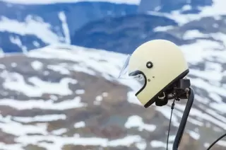 Motorcycle helmet resting on a motorcycle with a mountain backdrop