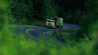 Semi truck driving on a road along a forest landscape