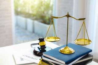 Gavel resting across a sound block along with symbolic court weighing scale