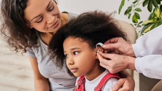 The Doctor is Placing a Hearing Aid Machine in Girl's Ear in Florida