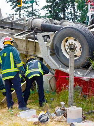 firemen trying to save person trapped from rollover truck accident