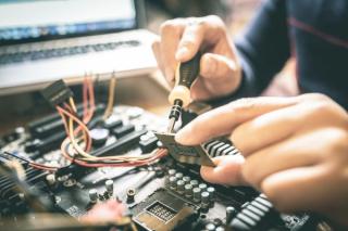 Person soldering a wire onto a chip to an engine computer for a Remanufactured Engine