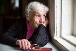 Senior women looking out window thinking about her life