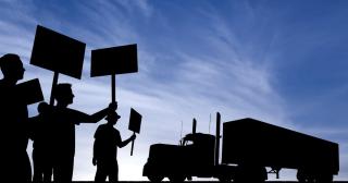 Protesters holding signs next to a semi truck