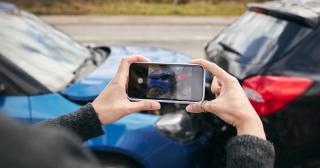 Man taking photo of car crash damage with cell phone