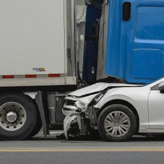 White car that has crashed with a blue semi truck