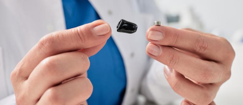 An audiologist at Elite Hearing Centers replaces hearing aid batteries
