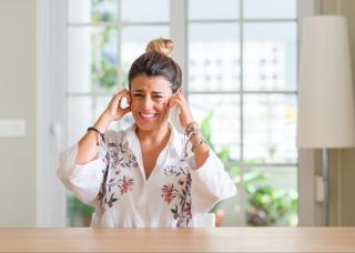 A woman suffering from hyperacusis holds her ears to find relief from loud noise