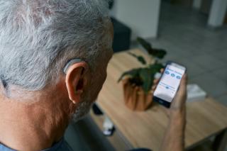 A man syncs up his hearing aids to be able to hear his phone conversations