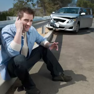 Man on mobile phone in front of car crash