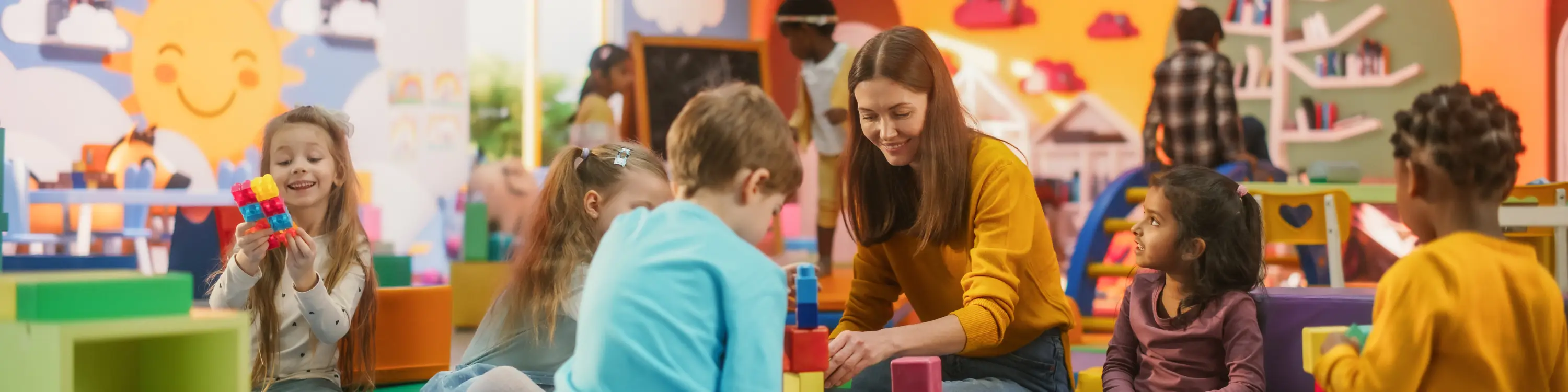 Kindergarten teacher enjoying building blocks with her students.