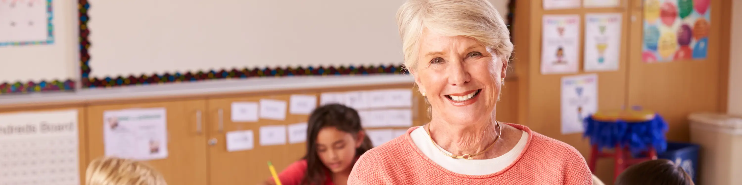 Middle aged teacher smiling in a classrom