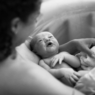 a woman holding her newborn child in black and white - dallas birth injury attorneys