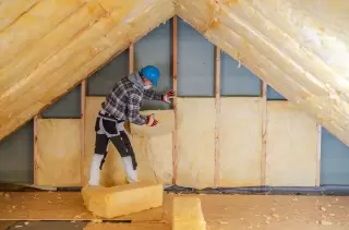 Installer adding insulation in the attic to improve energy costs