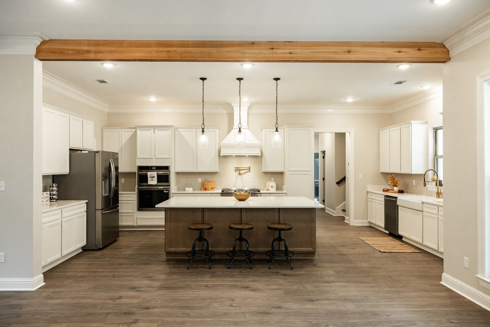 The Howell Custom Home — gourmet kitchen with quartz island, white cabinetry, stainless appliances, and brick fireplace great room built on the homeowner's property in Louisiana