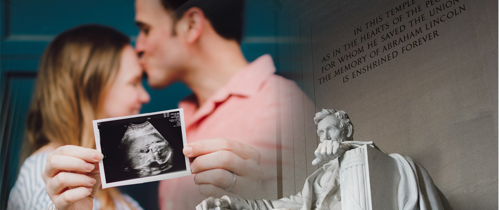 married couple holding up ultrasound of baby with Lincoln memorial in the background