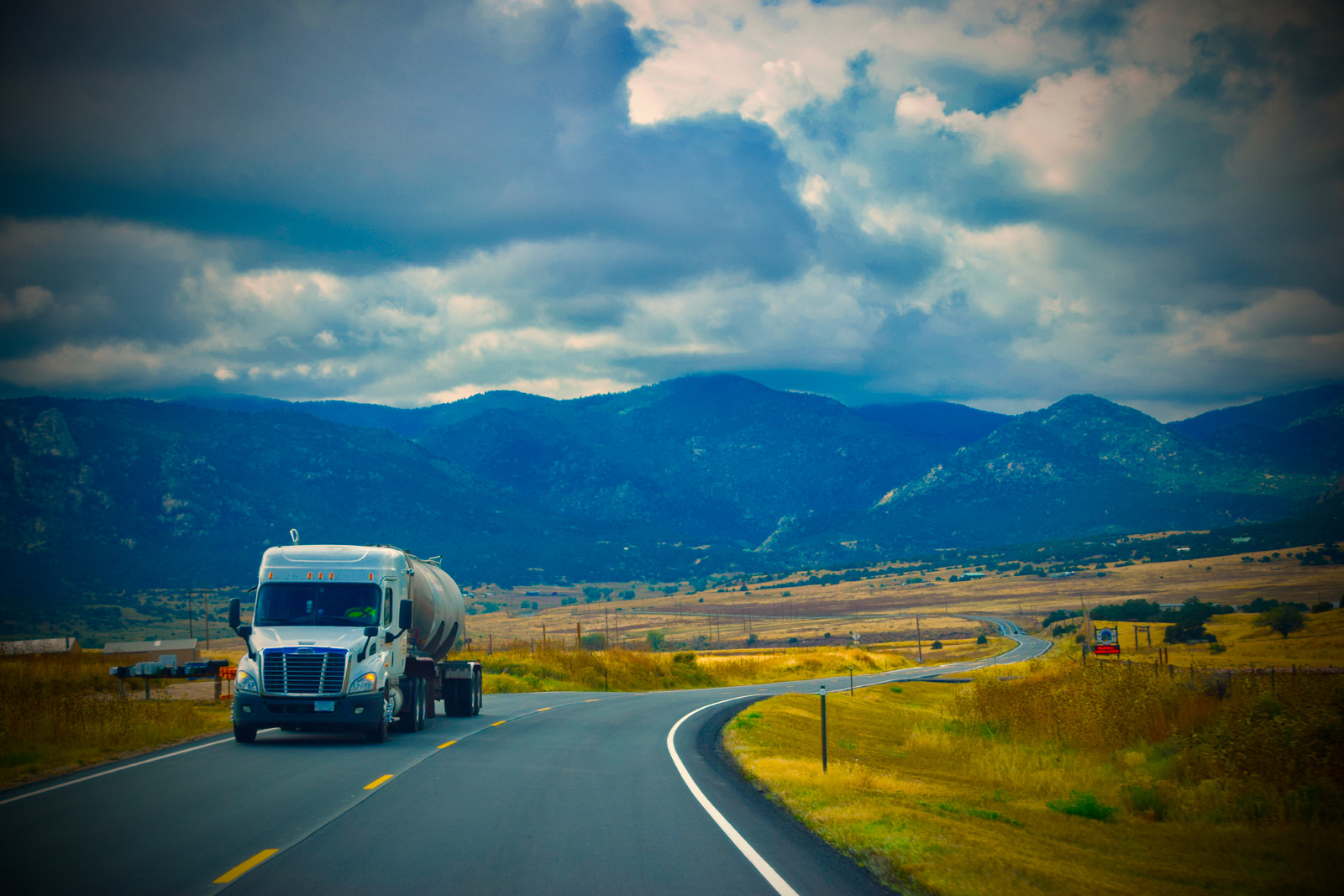Semi truck driving on a road along a vast landscape