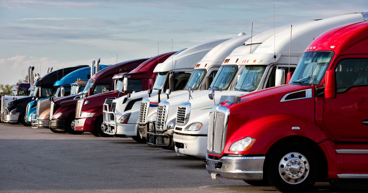 Several semi trucks parked next to each other in a parking lot