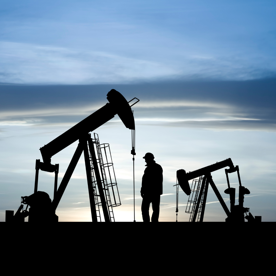 A man standing in between two oil derricks