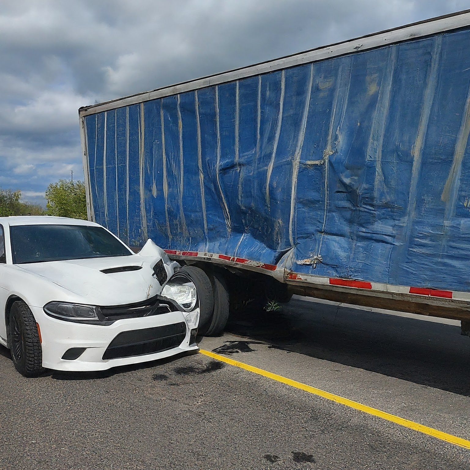 White car crashed into the side of semi truck trailer