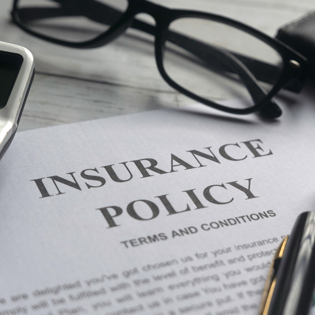 Insurance policy documents on a desk next to eyeglasses