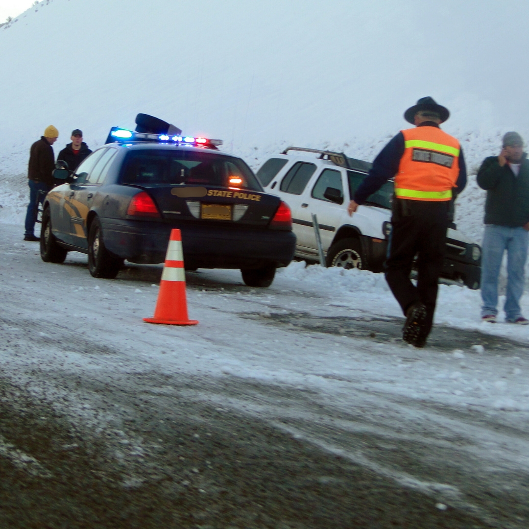 Car accident on side of snowy road with police officer