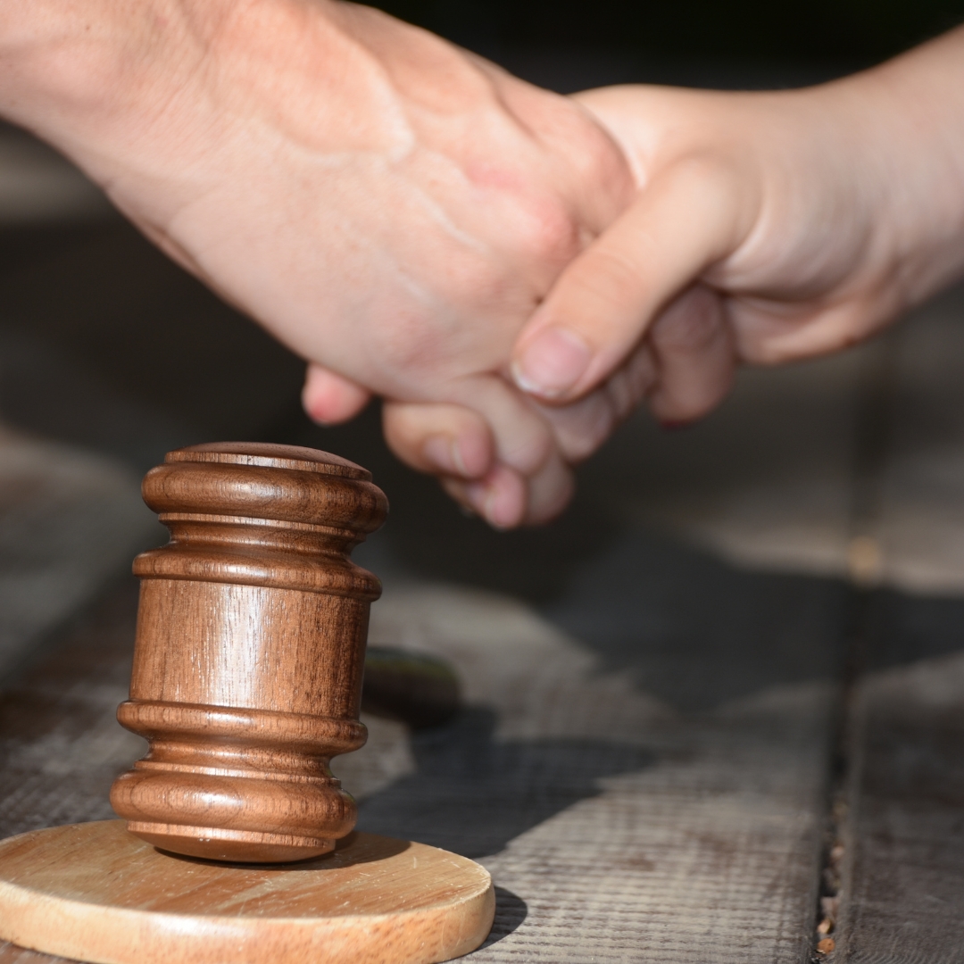 Shaking hands in agreement with a gavel on a desk