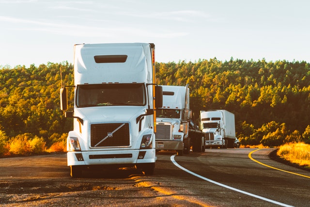 A group of white 18 wheelers travelling down the highway in Texas